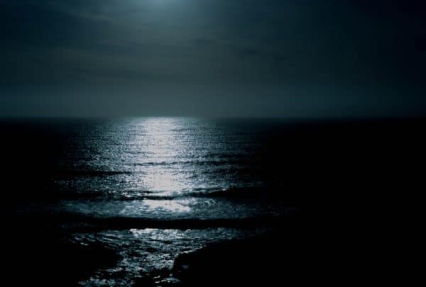 body of water under cloudy sky at night