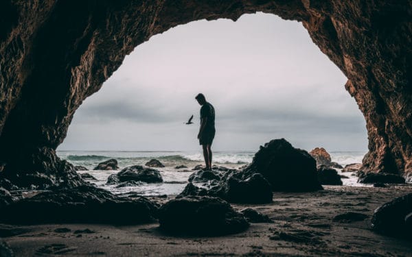 Photo of man standing on rock near seashore