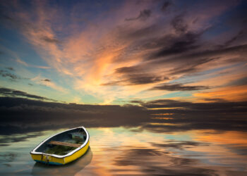 Beautiful vibrant blue and pink Winter sky with single boat floa