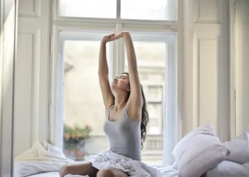 woman sitting on white bed while stretching